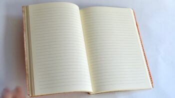 מחברת שורה מחופה בבד רך ירוק ובחזית ריקמה בכתום לסיומת