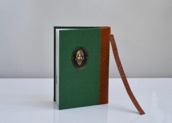 הספר מוכן עם הסימניה מהעור והמטבע בחזית